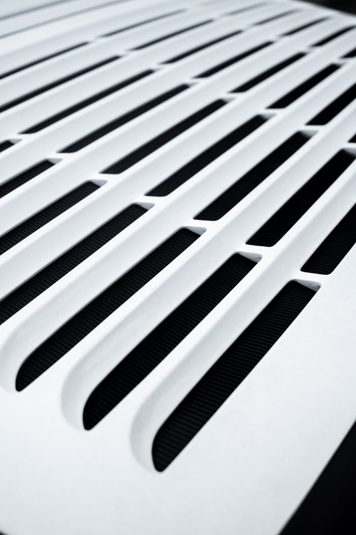 hero-img-01 Close-up of a white vent with a modern pattern, highlighting sleek design elements.